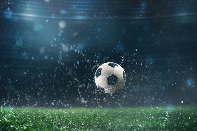 Football Bouncing in the Rain in Stadium