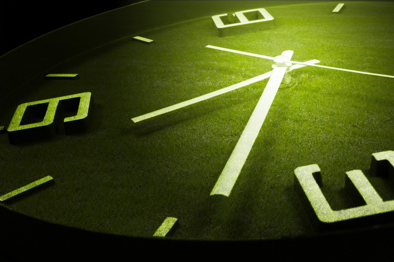 Clock Hands Against Grass Pitch